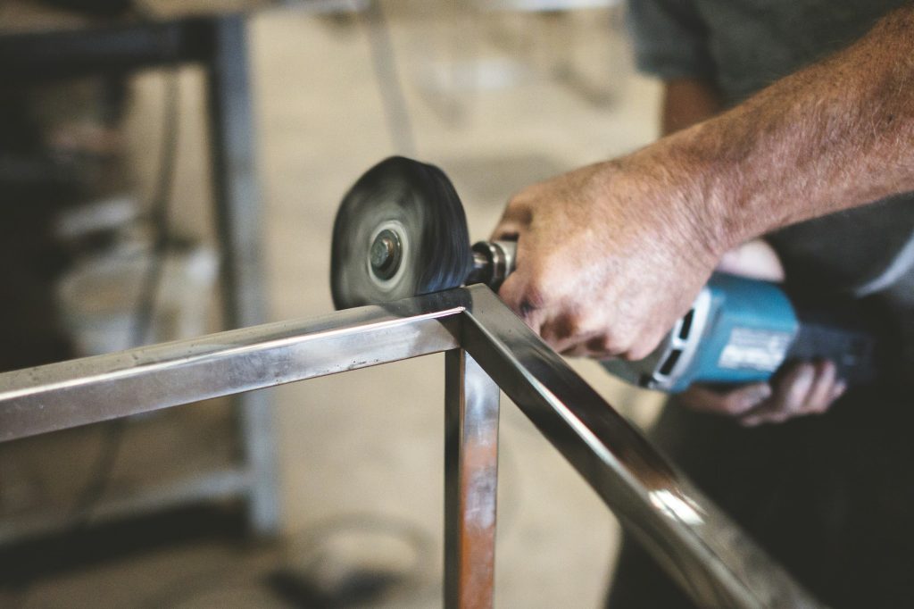 Closeup of a person polishing steel under the lights in a garage