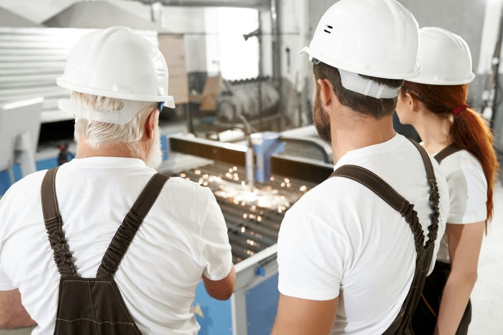 Engineers observing plasma laser cutting metal