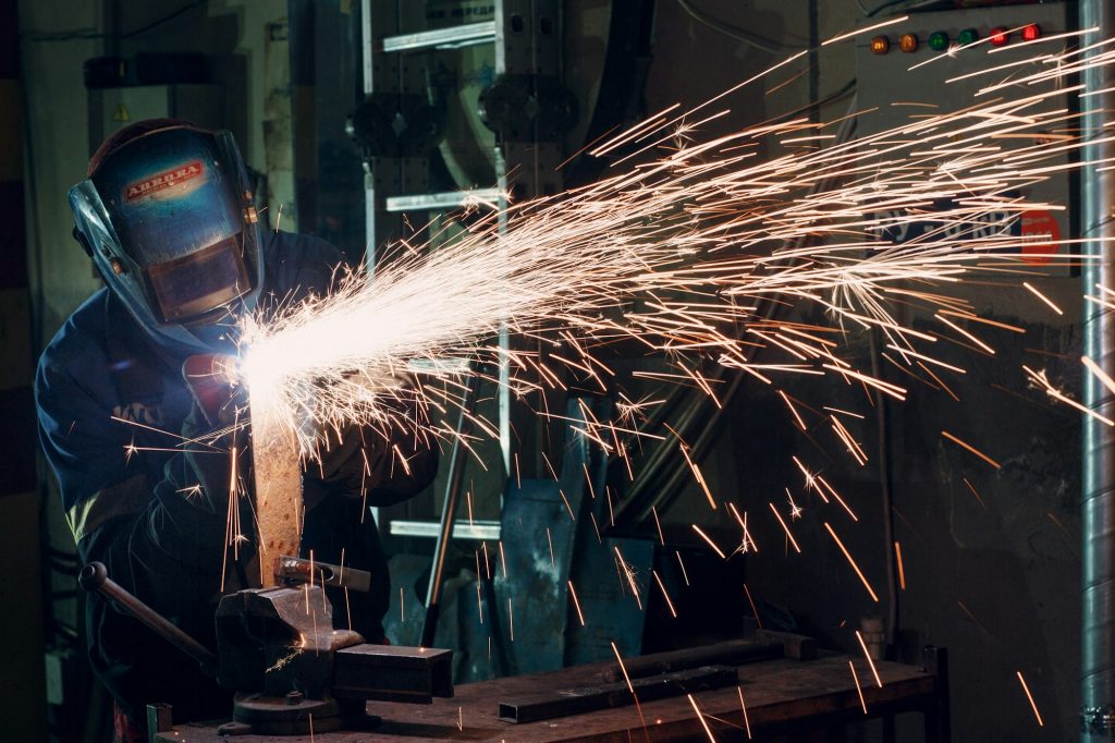 Man in mask cuts metal with plasma cutter. Helmet and spakrs